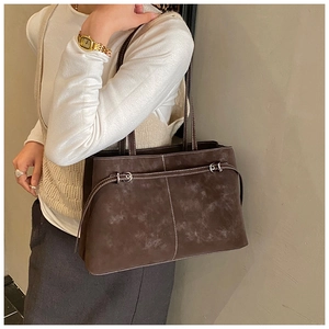 Close-up of brown suede tote bag with contrast stitching and metal buckle detail