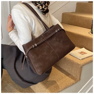 Detailed view of brown suede tote bag with white contrast stitching and metal belt buckle