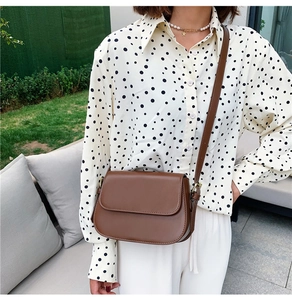 Detail of a vintage dark brown saddle bag shown in an outdoor lifestyle scene with a model