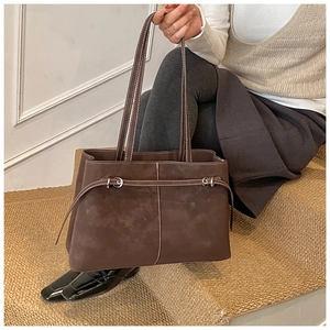 Detail of dark brown suede tote bag featuring white contrast stitching and long shoulder straps