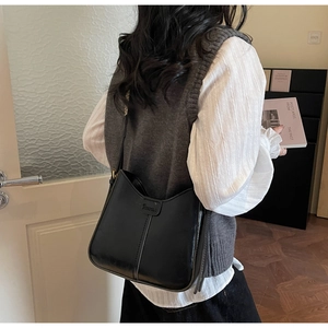 Black leather bucket bag with vertical stitching and adjustable strap on shoulder