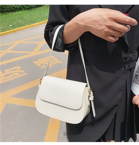 Close-up of a minimalist white half-moon shoulder bag with sleek gold hardware accents