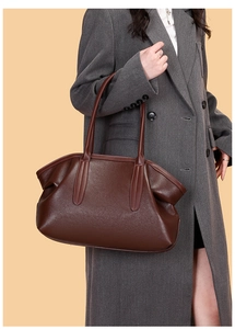Detail of deep brown pebble grain leather bowling bag styled with a grey winter coat