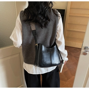 Detail showing the black PU leather crossbody bag with geometric woven shoulder strap