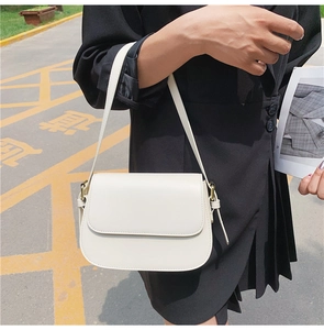 Close-up of beige crossbody bag with gold metal buckle and adjustable shoulder strap detail