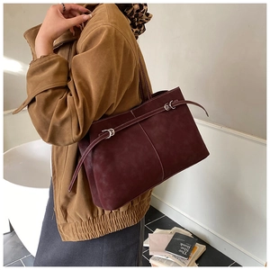 Detail of burgundy faux suede tote bag with slim straps and elegant metal buckle