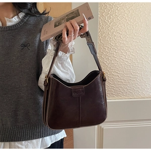 Detail of dark brown vintage leather shoulder bag with wide strap and embossed logo