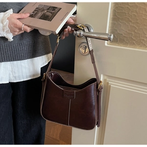 Close-up of a vintage dark brown shoulder bag with embossed logo hanging on a door handle
