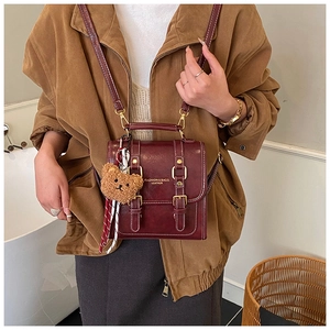 Détail du sac à dos vintage bordeaux avec boucle dorée et pendentif ours brun mignon
