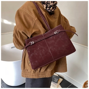 Detail of burgundy suede tote with white contrast stitching and silver buckle accent