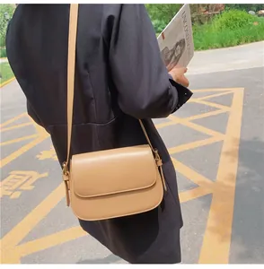 Outdoor shot showing the side profile of a khaki vintage shoulder bag worn by a model