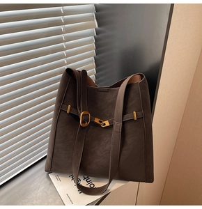 Detail of dark brown matte tote bag featuring gold buckle and dual strap design
