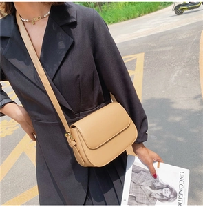 Detailed view of the khaki leather crossbody bag with flap cover and gold buckle hardware