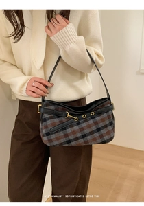 Detail of retro plaid underarm bag featuring leather strap and golden metal buckle eyelet
