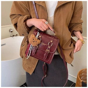 Détail du sac à dos vintage en cuir PU rouge vin avec boucles dorées et breloque ours