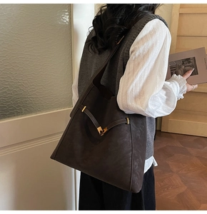 Rear view of large suede tote bag with wide strap and gold V-shaped metal clasp