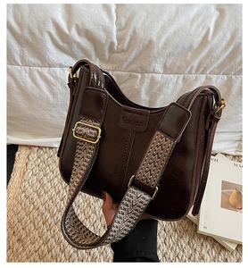 Close-up of retro brown leather bucket bag featuring a wide geometric woven shoulder strap