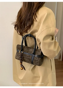Détail du sac vintage marron mat avec lanières en cuir noir et breloque cloche d'or