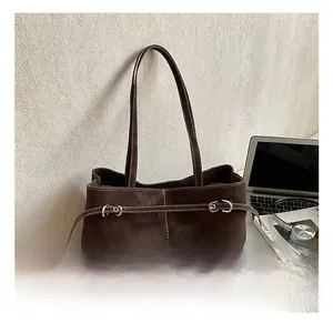 Detailed macro view of dark brown suede tote bag with white stitching and silver buckle