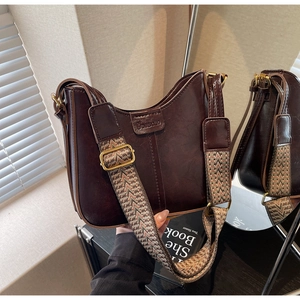 Detail of vintage brown leather bag with ethnic style woven strap and golden buckle