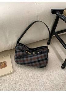Detail of vintage plaid shoulder bag with leather trim on soft plush carpet