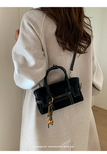 Detail view of black retro handbag with contrast stitching and metal ball charm
