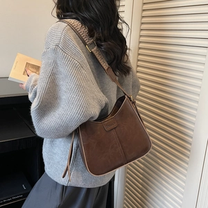 Close-up of vintage brown leather underarm bag featuring a wide bohemian jacquard strap