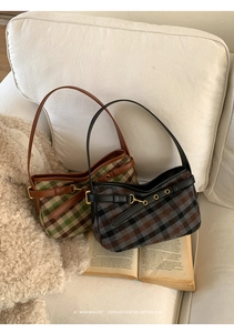 Detail of retro plaid underarm bag with metal buckle and wool texture on white sofa