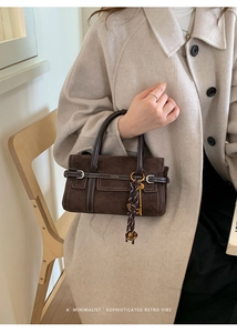 Detail of dark brown faux suede Boston bag with contrast stitching and retro charm charm