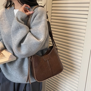 Detail of vintage brown shoulder bag featuring textured finish and woven geometric strap