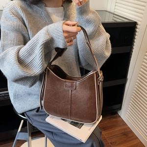 Detail of adjustable wide shoulder strap and gold hardware on brown saddle bag