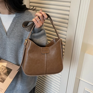 Detail of brown retro handbag with white contrast stitching and woven shoulder strap