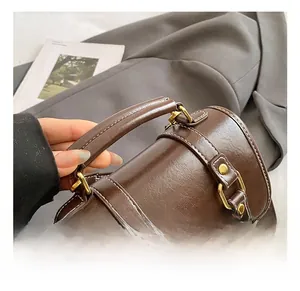 Détail de la poignée ronde en cuir et lettrage doré sur le sac à dos marron foncé