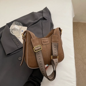 Detail of vintage brown crossbody bag featuring wide textured strap on a clean setup