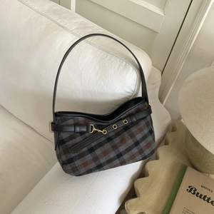 Retro checkered shoulder bag with brown plaid fabric and black leather trim on sofa