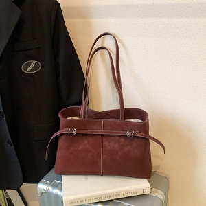 Burgundy suede tote bag with silver buckle and inner pouch on a white book backdrop