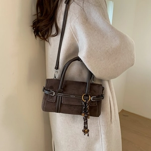 Sac à main minimaliste en daim marron foncé avec coutures blanches et pendentif tressé