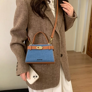 Sac à main rétro en denim et cuir marron avec fermoir doré porté par un mannequin
