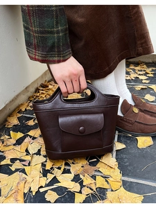 Detail of dark brown leather basket bag with front pocket in autumn street setting