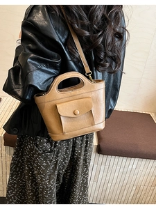 Close-up of camel leather handbag with front pocket worn by model in street style