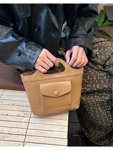 Detail of camel leather handbag with unique circular handle and front flap pocket button