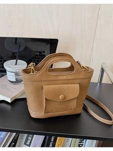 Detail of a brown leather basket bag featuring gold hardware and a front flap pocket