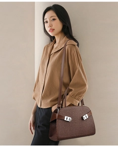 Detail of a brown woven texture handbag with silver buckle on a stylish model