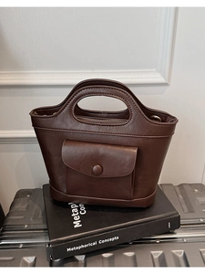 Detail of dark brown leather handbag with envelope pocket and cutout handle design