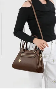 Detail der dunkelbraunen Handtasche aus genarbtem Leder mit goldenen Elementen und Reißverschluss