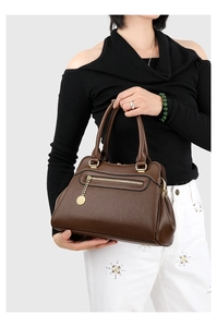 Detailansicht der braunen Handtasche mit Litschi-Textur und goldenen Metallanhängern