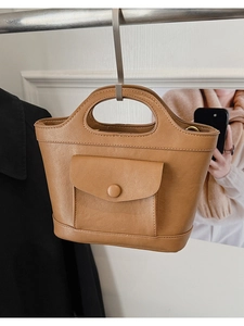 Detail view of brown leather handbag featuring a practical front flap pocket and sturdy handle