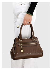 Details der dunkelbraunen Lederhandtasche mit goldenem Reißverschluss und Anhänger