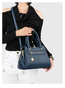 Detail der dunkelblauen Handtasche aus Kieselleder mit goldenen Reißverschlüssen