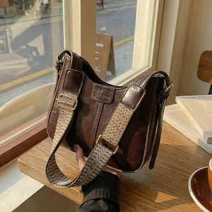 Retro dark brown crossbody bag with wide patterned strap on a cafe window seat